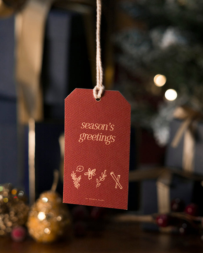 My Brunch Plans' gift tag with "season's greetings" text hanging against a festive background.