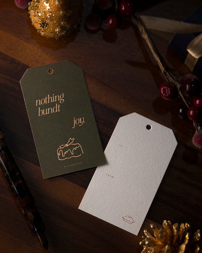 Front and back of My Brunch Plans' gift tags with "nothing bundt joy" and a bundt cake on a wooden surface with decorative elements.