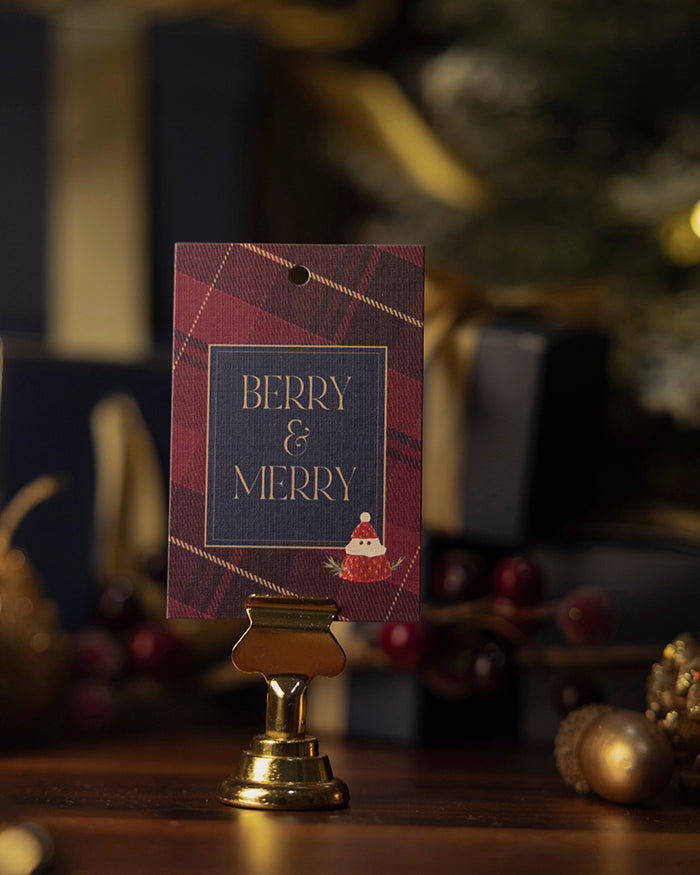 My Brunch Plans' tartan linen gift tag with 'Berry & Merry' text with a strawberry and creme santa on a stand against a festive background.