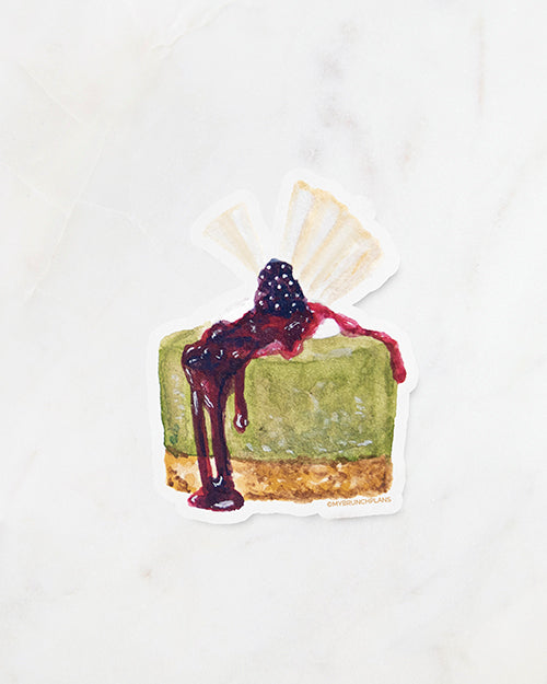 My Brunch Plans' hand painted gouache matcha cheesecake with blackberry compote and white chocolate topper diecut vinyl sticker with the paper backing on a marble background.