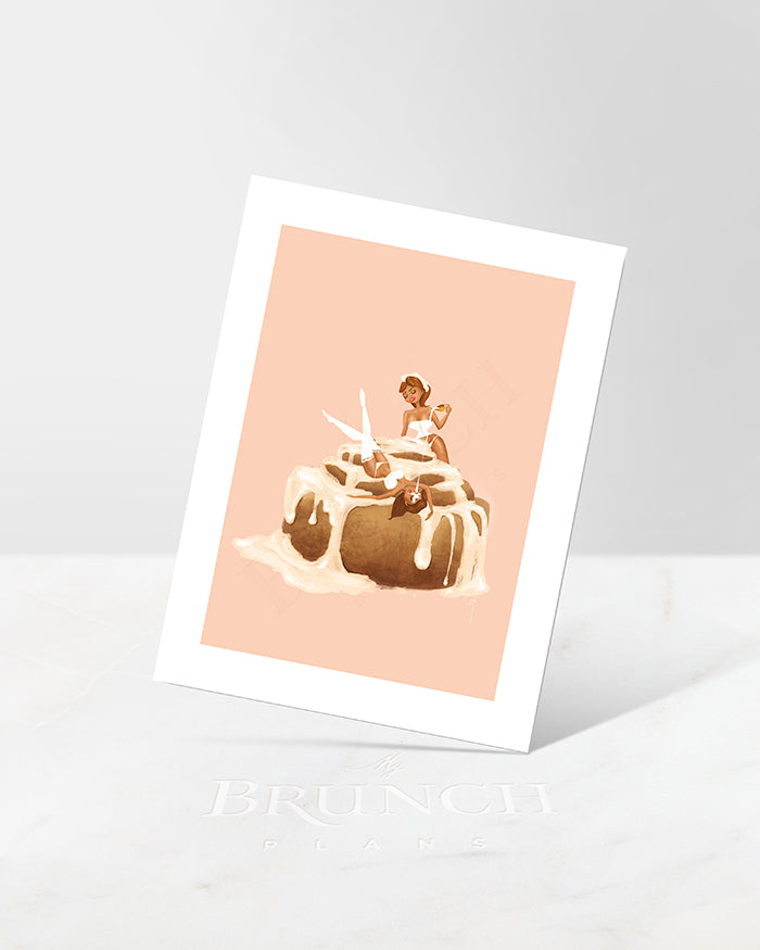 An art print featuring an illustration of a cinnamon roll with pinup women on a light background, placed against a marble background.