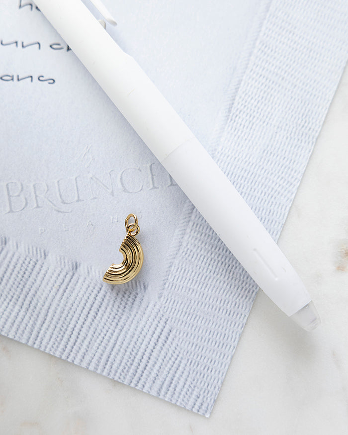 Macaroni Charm | 18k Gold Plated on My Brunch Plans’ Napkin notepad with a pen for size comparison.