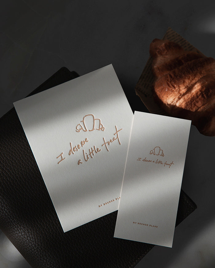 Two white cards with letterpress text on a dark surface