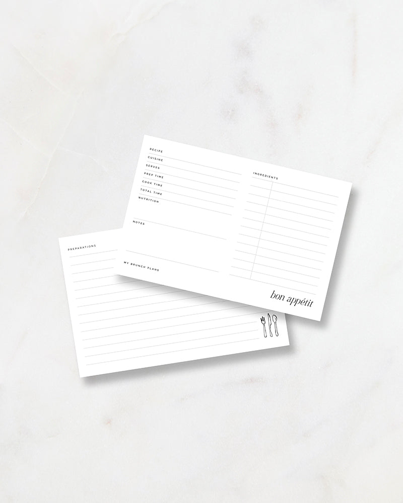 My Brunch Plans’ designed recipe card showing front and back placed on a marble surface. Front is minimal with a italic bon appetit on the bottom and the back has ink drawn utensils on the bottom corner.