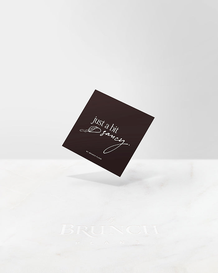 My Brunch Plans' pplanner card with a rich dark brown and the phrase "just a bit" written in a serif typeface and "saucy" in a handwritten cursive typeface alongside a handdrawn line art taco with sauce dripping out on a marble background.