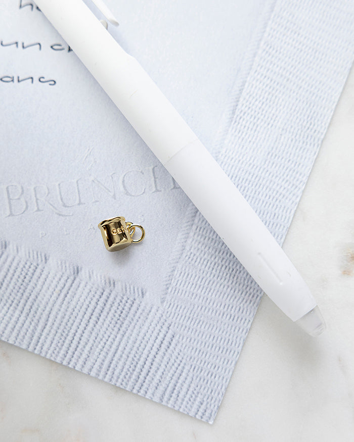 Cafe Mug Charm | 18k Gold Plated on My Brunch Plans’ Napkin notepad with a pen for size comparison.