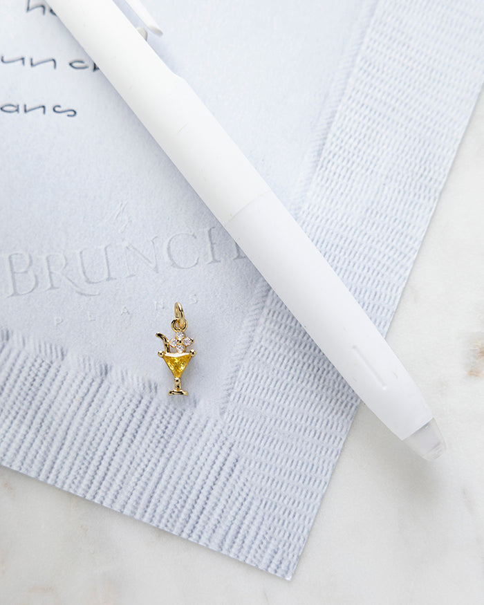 Cocktail Charm | 18k Gold Plated with CZ on My Brunch Plans’ Napkin notepad with a pen for size comparison.