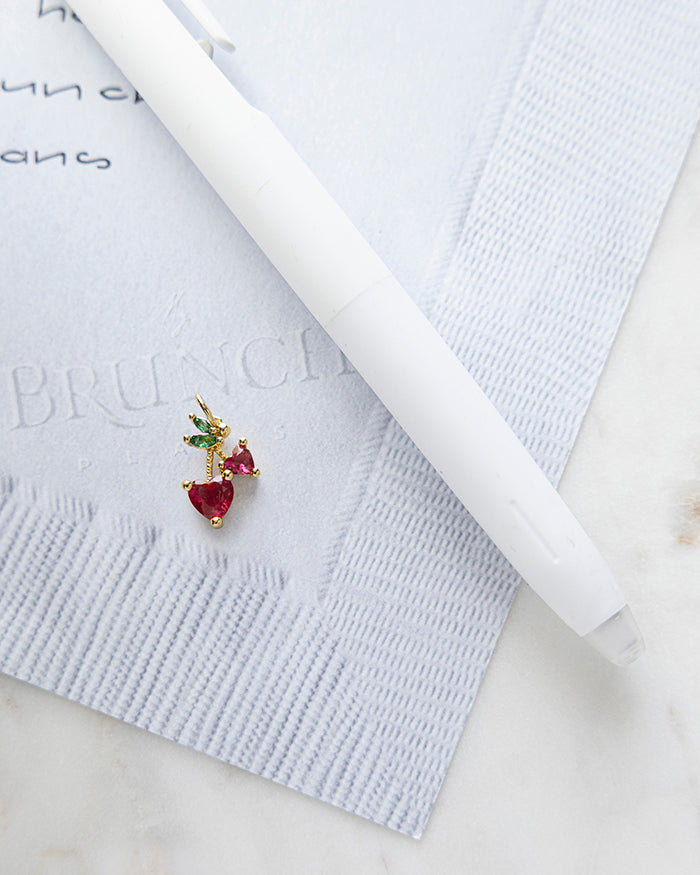 Heart Cherries | 18k Gold Plated with CZ on My Brunch Plans’ Napkin notepad with a pen for size comparison.