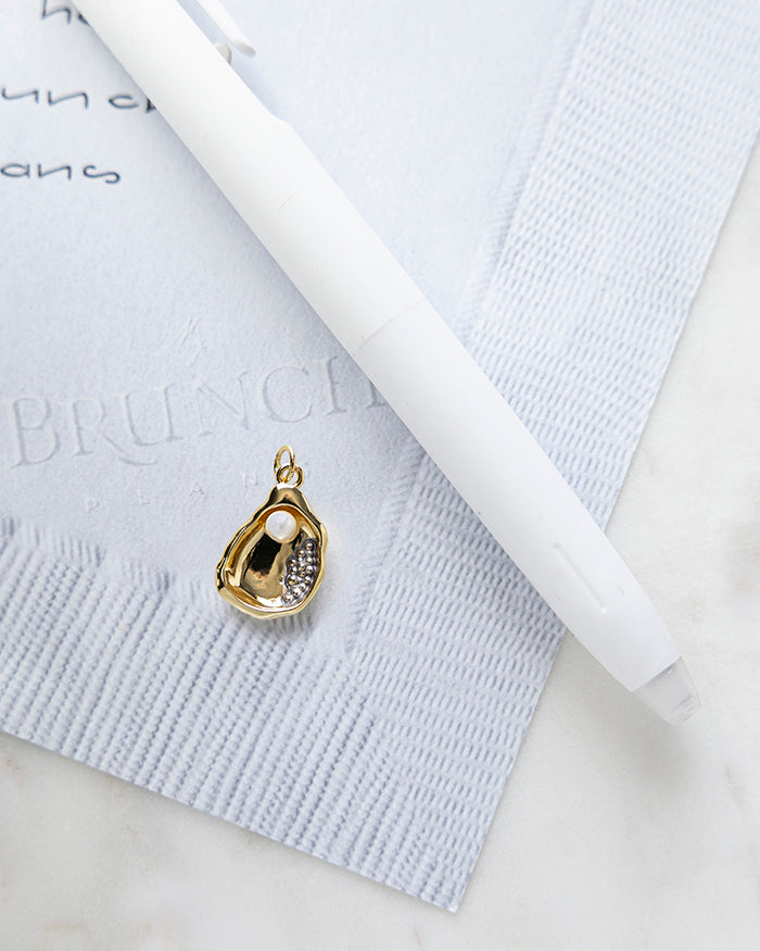 Oyster with Pearl Charm | 18k Gold Plated on My Brunch Plans’ Napkin notepad with a pen for size comparison.