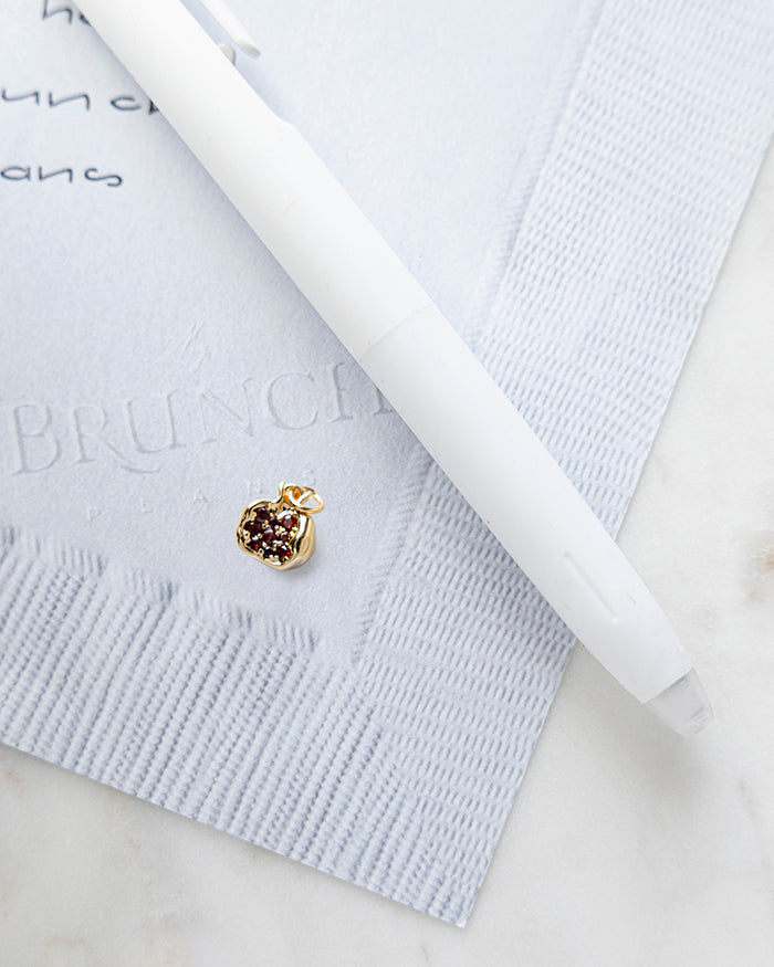 Gold Pomegranate Charm | 16k Gold Plated on My Brunch Plans’ Napkin notepad with a pen for size comparison.