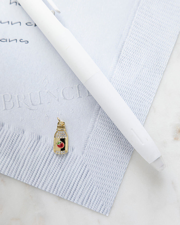 Strawberry Drink Charm | 18k Gold Plated with CZ on My Brunch Plans’ Napkin notepad with a pen for size comparison.