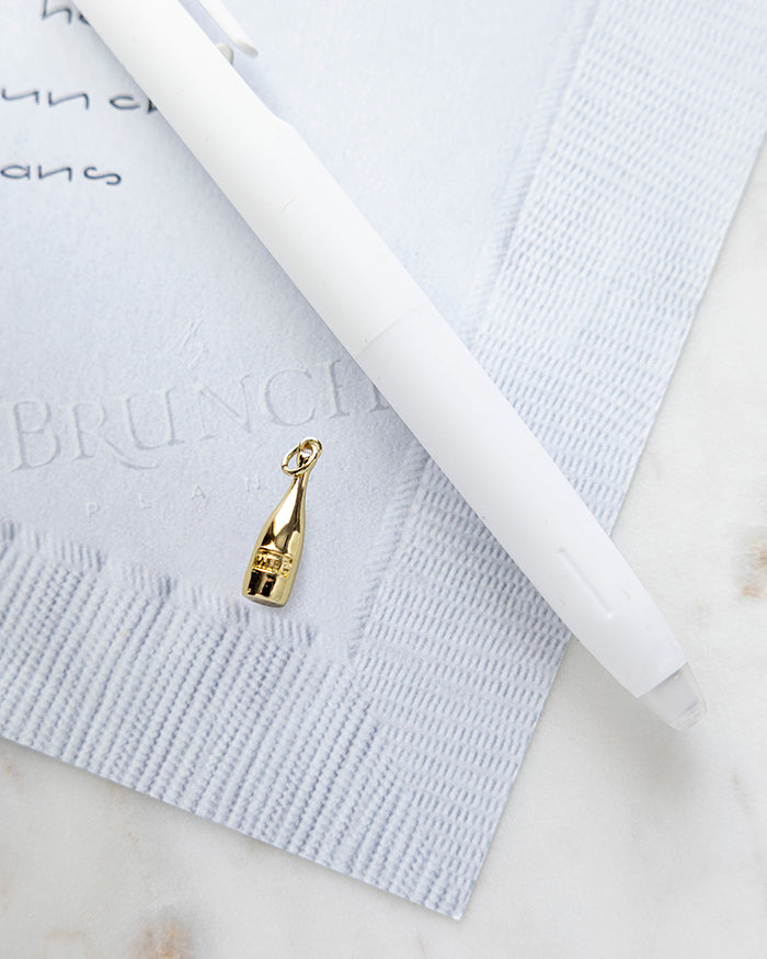 Wine Bottle Charm | 22k Gold Plated on My Brunch Plans’ Napkin notepad with a pen for size comparison.